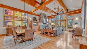 A spacious living area with a wooden dining table, chairs, and a stone fireplace. - Northstar Ski-In/Ski-Out with Hot Tub & Views (Northstar)