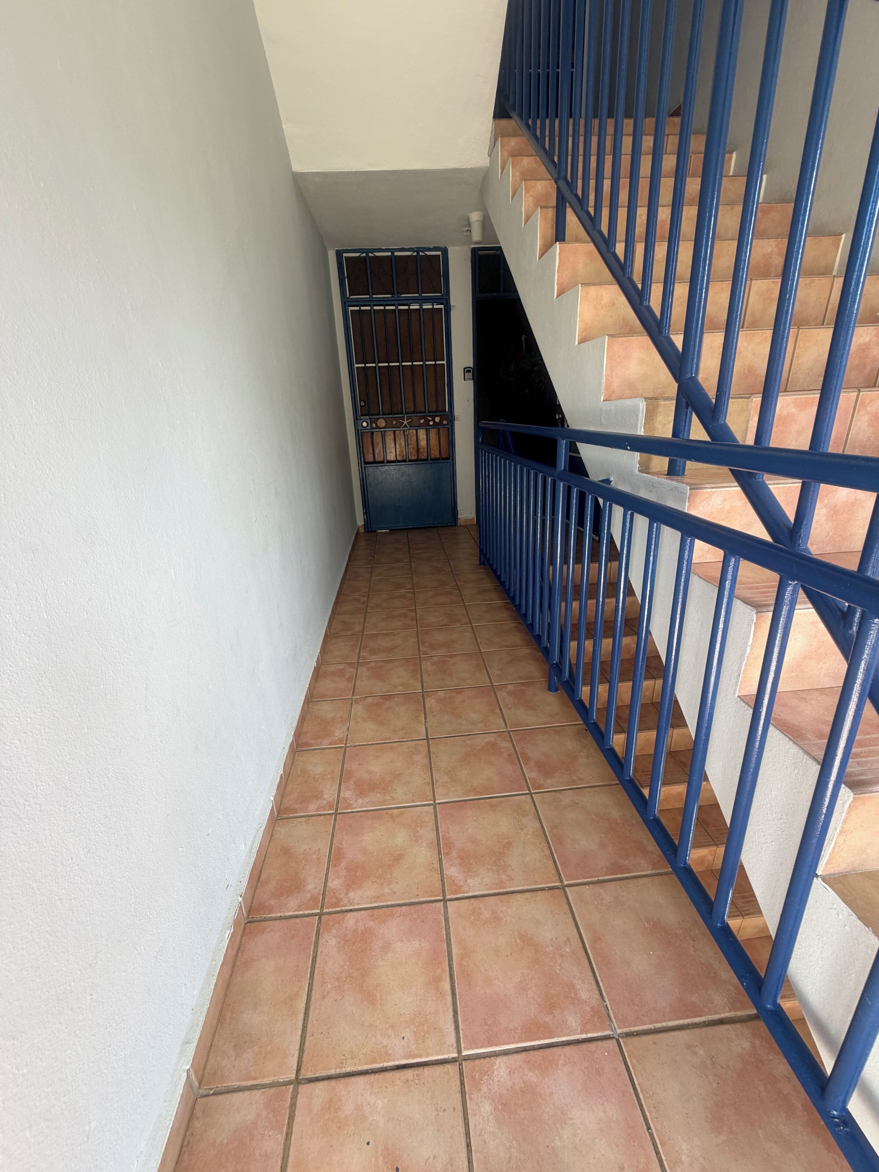 Una escalera con barandillas azules y suelo de baldosas.