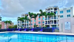 A swimming pool with lounge chairs and a blue fence.