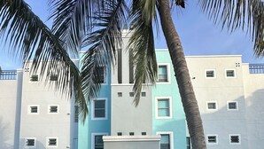 A building with a central entrance, blue and white exterior, and a blue metal railing in front.