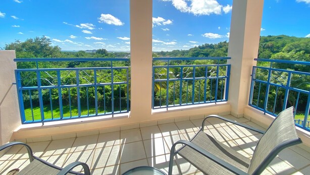 A balcony with a view of a green landscape and a clear blue sky.