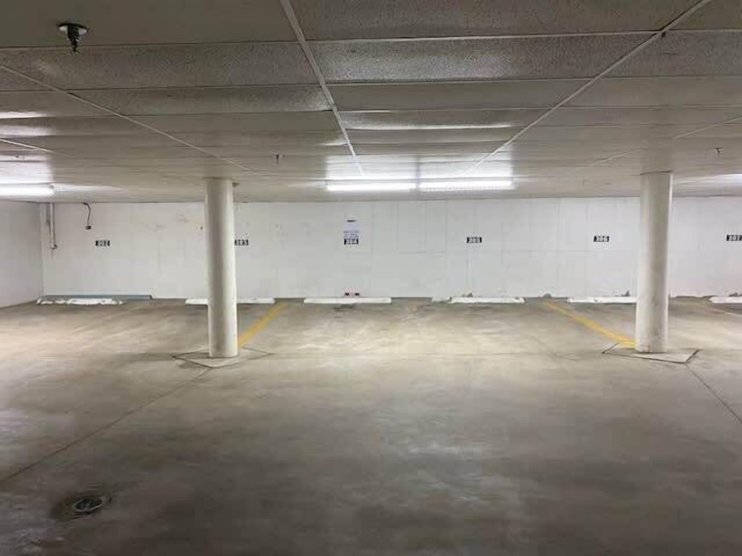 A spacious parking garage with concrete pillars and white walls.