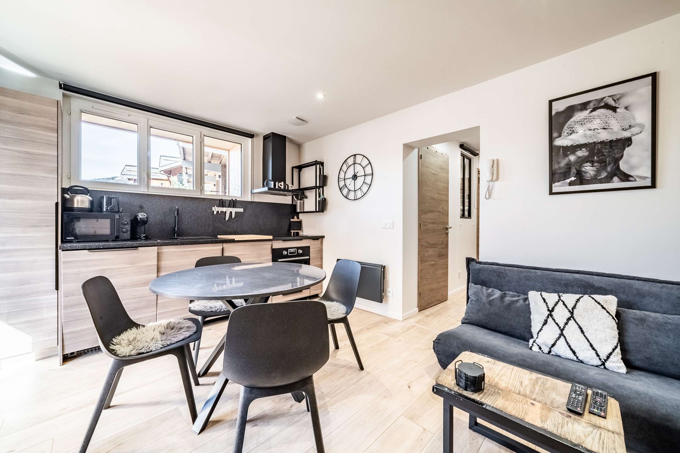 A modern kitchen with a dining area, a sofa, and a coffee table.