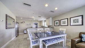 Un comedor con una mesa y sillas, un refrigerador y una cocina al fondo.