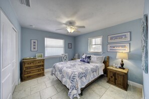 A bedroom with a bed, dresser, nightstands, and a ceiling fan. - Ocean Breeze Beach Bungalow (Ormond Beach)