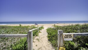 Acceso a la playa con una puerta de madera y un letrero que indica propiedad privada.