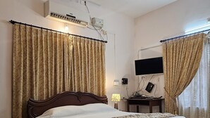 Une chambre avec un grand lit, un ventilateur de plafond, une télévision et un bureau avec une lampe.
