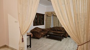 Un salon avec un canapé marron, une table basse en verre et un meuble adossé au mur.