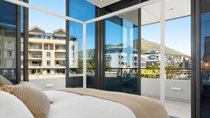 Una habitación de hotel moderna con una cama grande, vistas a la ciudad y un balcón con piscina.