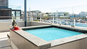 Una piscina en la azotea con vistas despejadas al puerto deportivo y edificios circundantes.