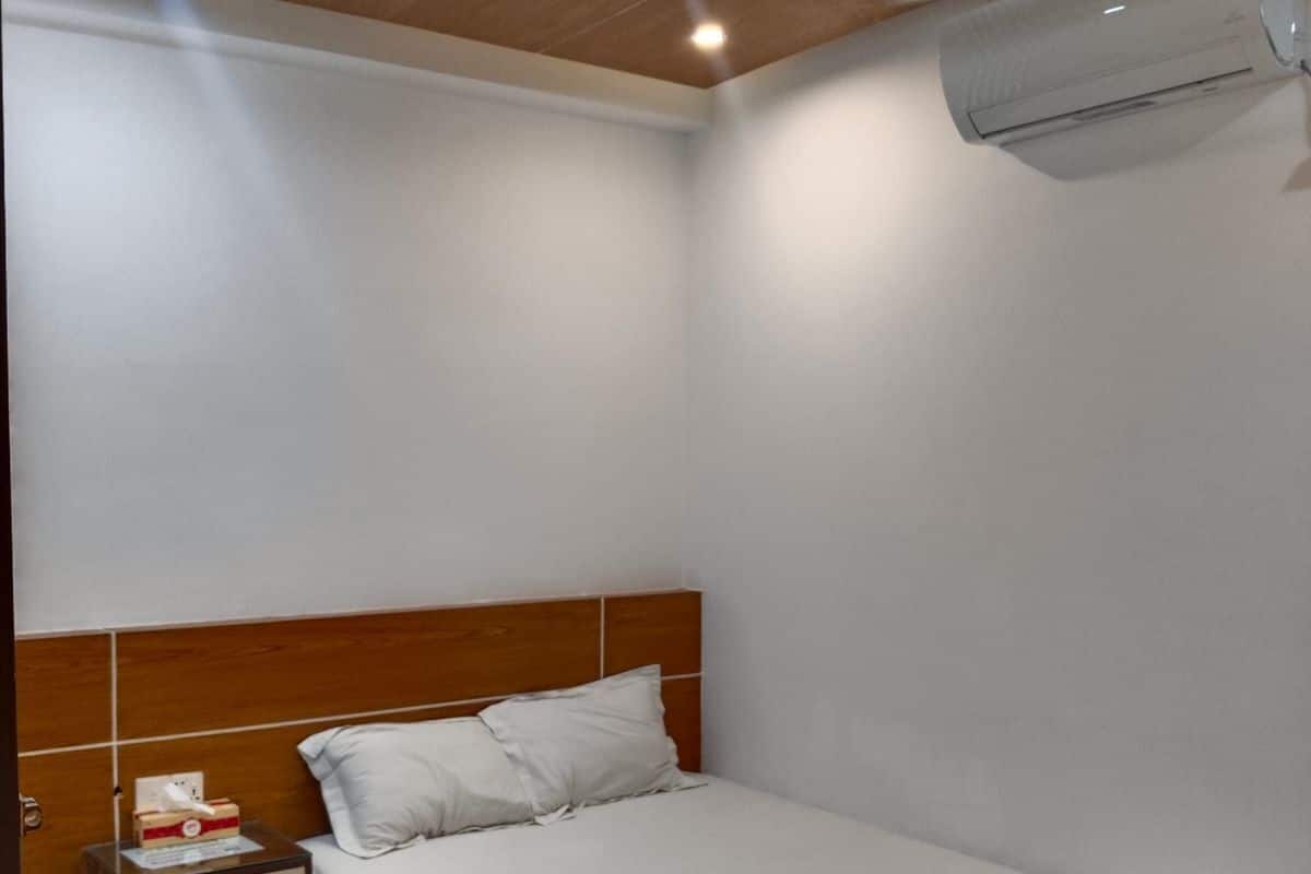 Ein Schlafzimmer mit Holz-Kopfteil, einem Einzelbett, einem Nachttisch und einer Klimaanlage.