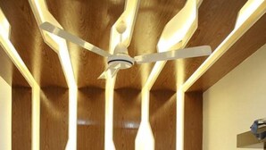 Une chambre d’hôtel avec un lit, une tête de lit en bois et un ventilateur de plafond.