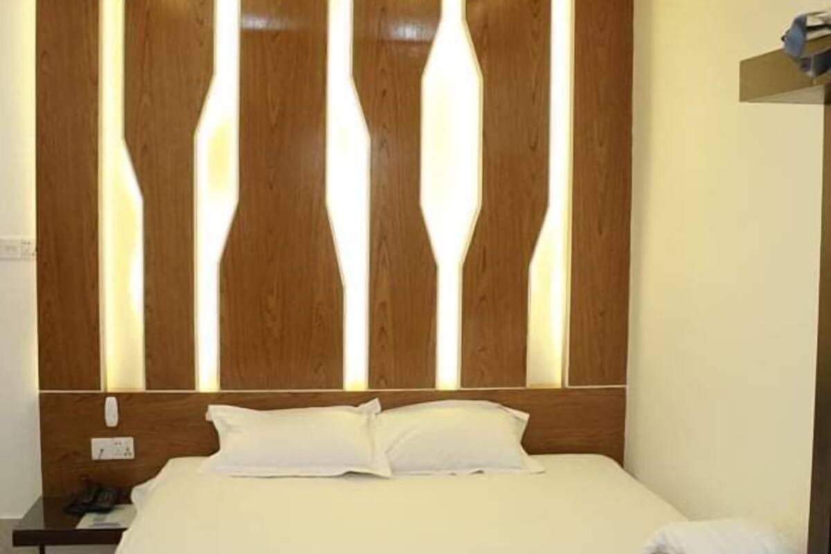 Ein Hotelzimmer mit Bett, Holz-Kopfteil und Deckenventilator.