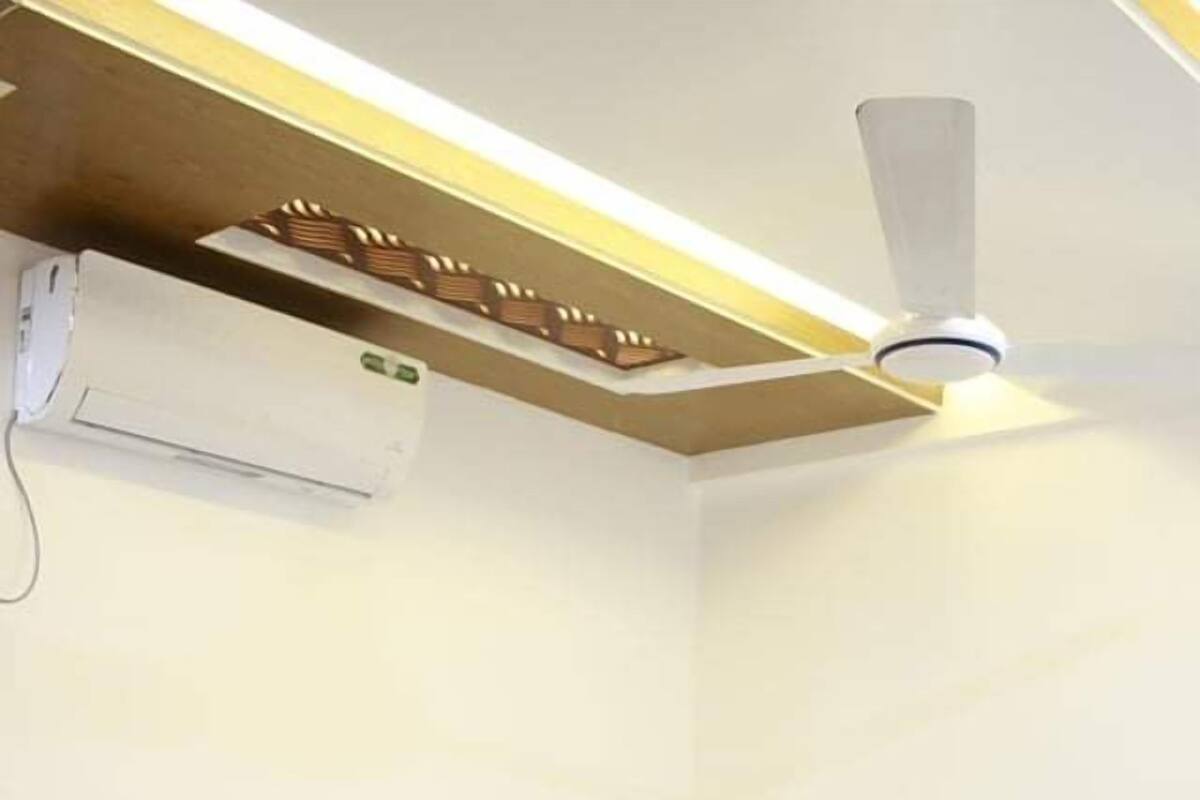 Ein Hotelzimmer mit Bett, weißen Leinen, Deckenventilator und Klimaanlage.