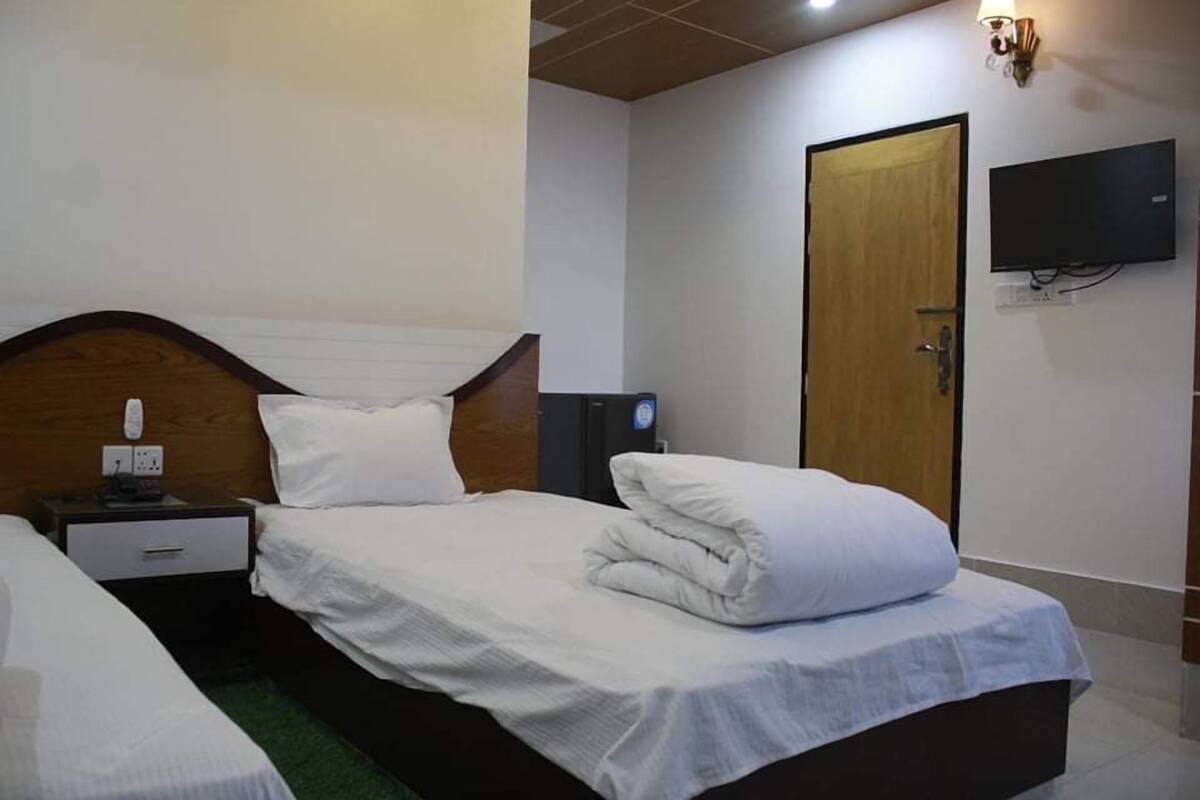 Ein Hotelzimmer mit einem Bett, einem Nachttisch und einem an der Wand befestigten Fernseher.