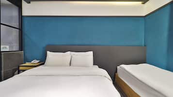 Una habitación de hotel con una cama grande, una mesita de noche con teléfono y una lámpara.