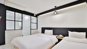 Ein modernes Hotelzimmer mit einem großen Bett, einem Nachttisch mit Telefon und einem Fenster mit satinierten Glasfeldern.