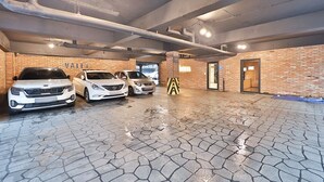 Eine Parkgarage mit drei Autos, freiliegenden Rohren und einer Ziegelwand.