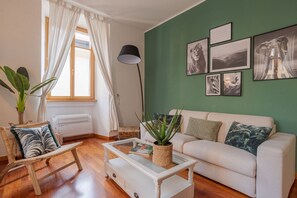 A living room with a sofa, a coffee table, a chair, a lamp, and wall art. - Urban Oasis - My Home in Como (Como)