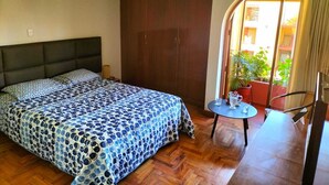 A bedroom with a bed, a wardrobe, a small table with items, and a view of the outside. - Beautiful 3-bedroom apartment 4 blocks from the main square of Arequipa! (Arequipa)
