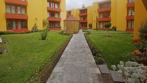 A courtyard with yellow buildings, a central pathway, and well-maintained lawns. - Beautiful 3-bedroom apartment 4 blocks from the main square of Arequipa! (Arequipa)