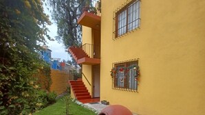 A yellow building with a staircase, a large pot, and a garden with red flowers. - Beautiful 3-bedroom apartment 4 blocks from the main square of Arequipa! (Arequipa)