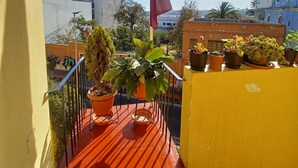 A balcony with potted plants, a flag, and a view of buildings. - Beautiful 3-bedroom apartment 4 blocks from the main square of Arequipa! (Arequipa)