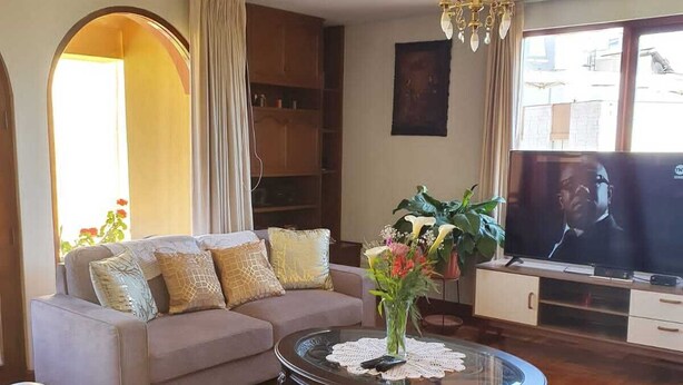 A living room with a sofa, armchair, coffee table, TV, and bookshelf. - Beautiful 3-bedroom apartment 4 blocks from the main square of Arequipa! (Arequipa)
