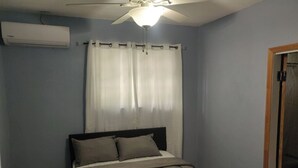 A bedroom with a bed, a ceiling fan, and a window with curtains. - Charming family friendly home,furnished with parking facilities,near malls/beach (Nassau)