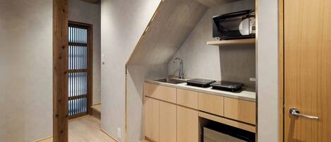 A compact kitchen with wooden cabinets, a built-in sink, and a microwave.