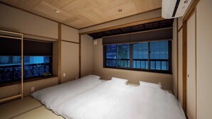 Une chambre avec un grand lit, une fenêtre avec des stores et un ventilateur de plafond.