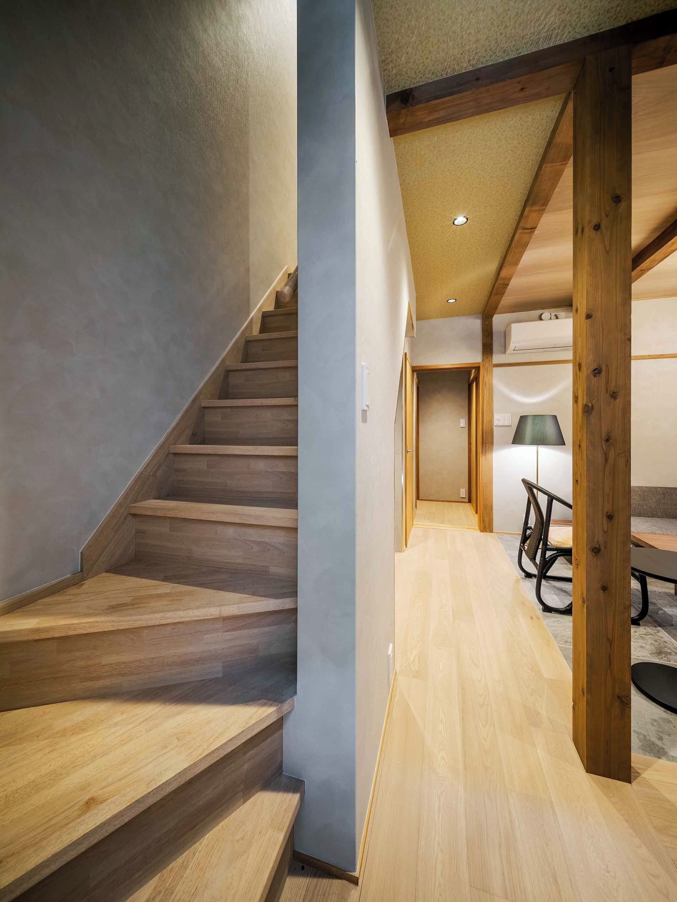 A modern interior with a wooden staircase, a dining area with a table and chairs, and a ceiling with exposed beams.