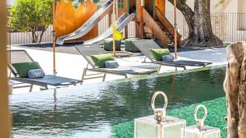 An outdoor swimming pool with lounge chairs and a slide.