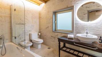 Een badkamer met een douchecabine, een wit toilet, een wastafel met spiegel en een houten wastafelmeubel.