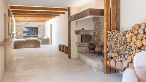 Uma sala de estar ampla com lareira de pedra, parede de pedra e teto de madeira.
