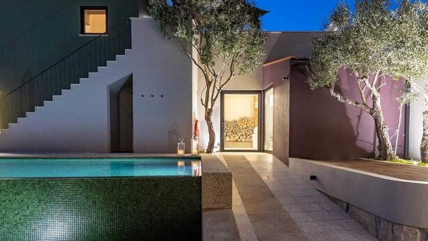 Et moderne hus med swimmingpool, trappe og træer.