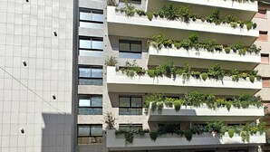 A modern building with multiple balconies, each adorned with green plants. - Zeta Rentals  (Bari)