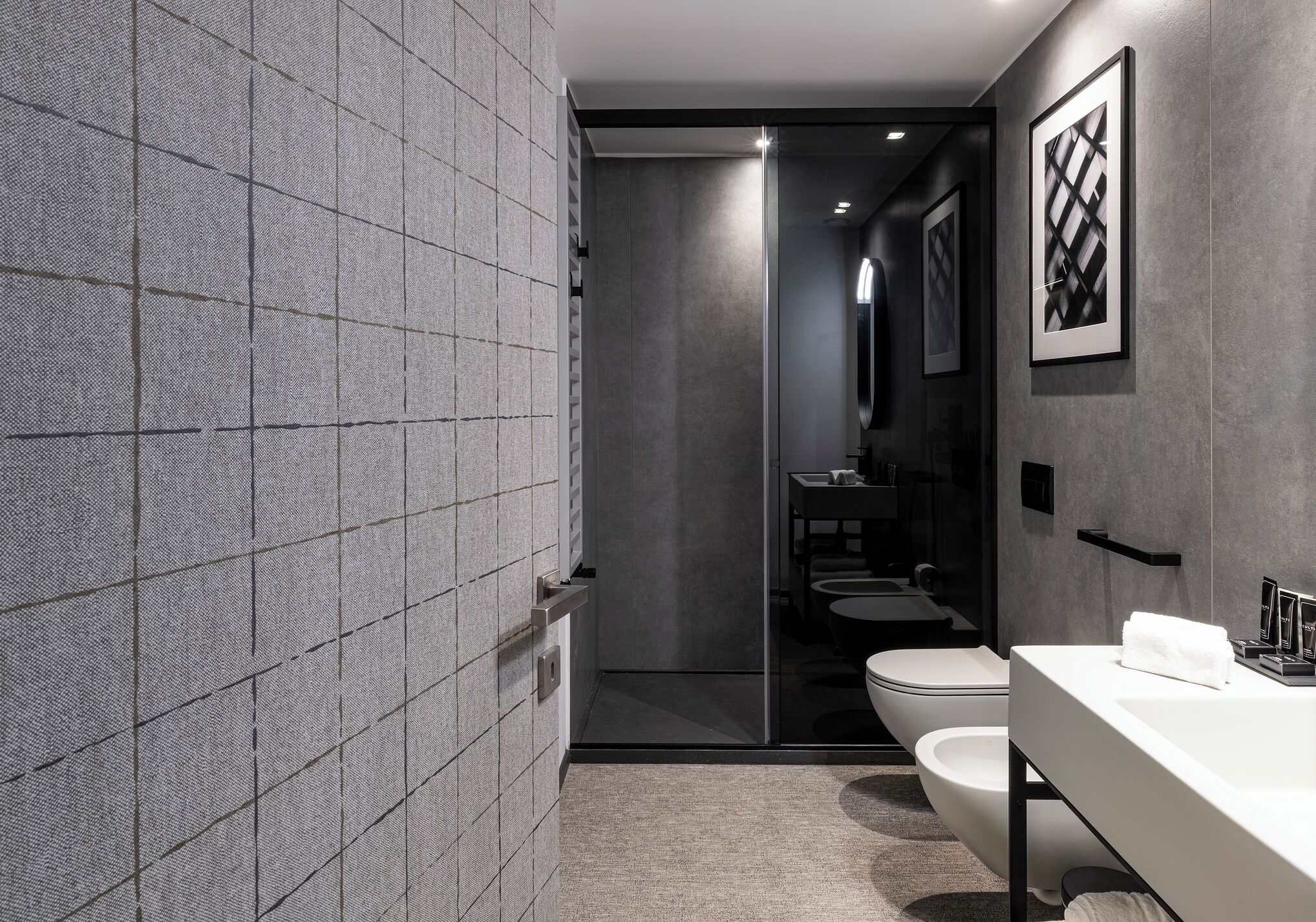 A modern bathroom with a large mirror, a toilet, and a bidet.
