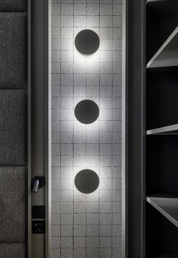 Un mur moderne agrémenté de trois luminaires circulaires et d’un panneau de commande.