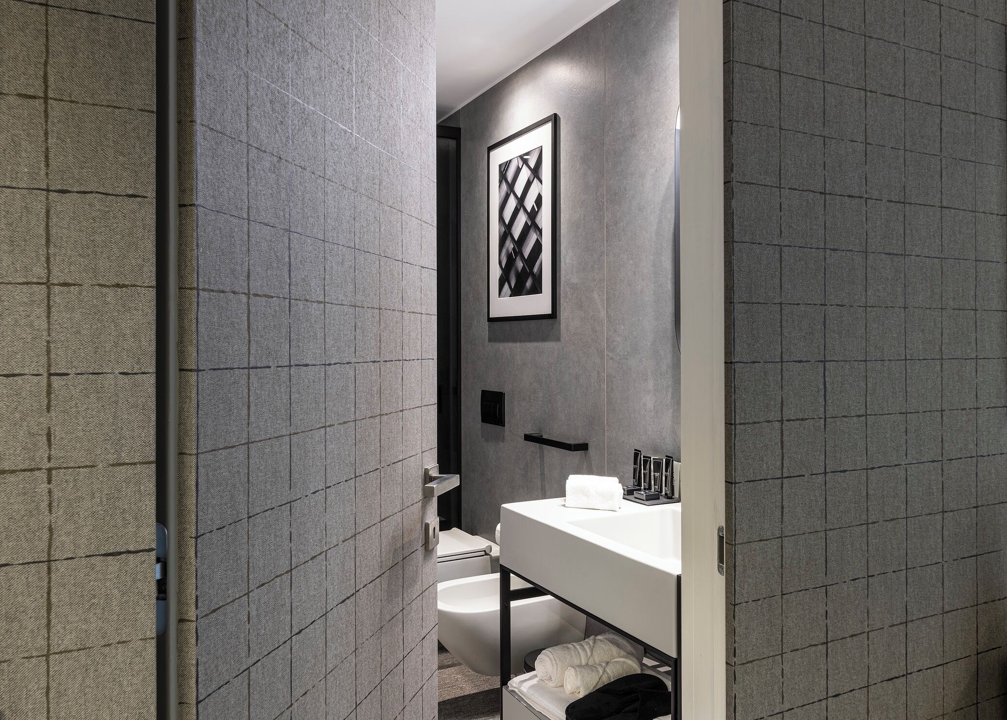 A modern bathroom with a white sink, a toilet, and a towel rack.