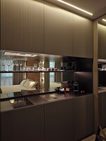A modern hotel room with a kitchenette, a bed, and a large mirror.