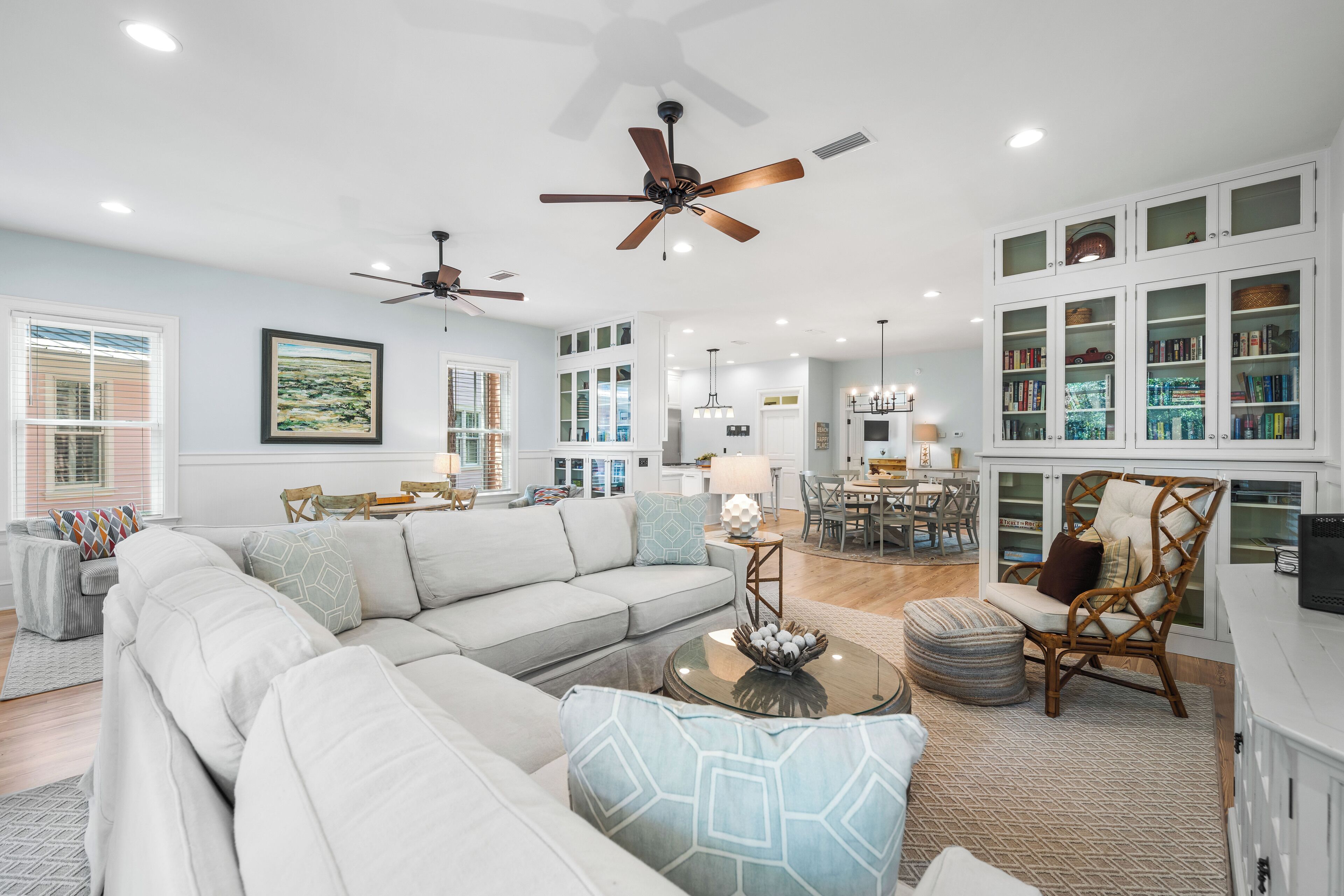 A spacious living room with a large sectional sofa, a dining area, and a kitchen with white cabinetry.