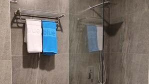 Een moderne badkamer met een douchecabine van glas, een toilet en een handdoekrek met twee handdoeken.