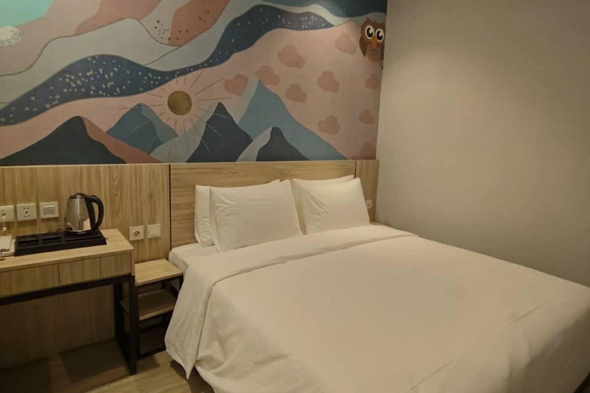 Une chambre d’hôtel avec un lit, un bureau et une fresque murale.