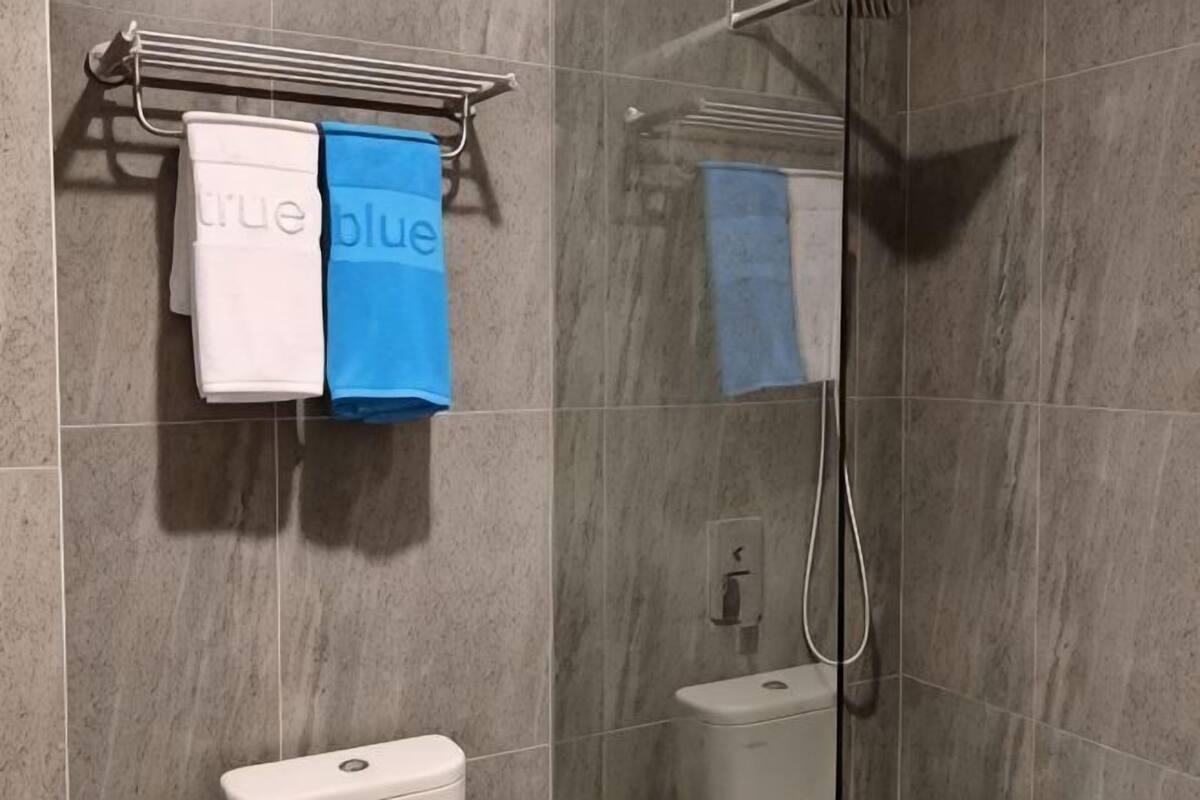 Une salle de bain équipée de toilettes, d’une douche et de deux serviettes suspendues à un porte-serviettes.