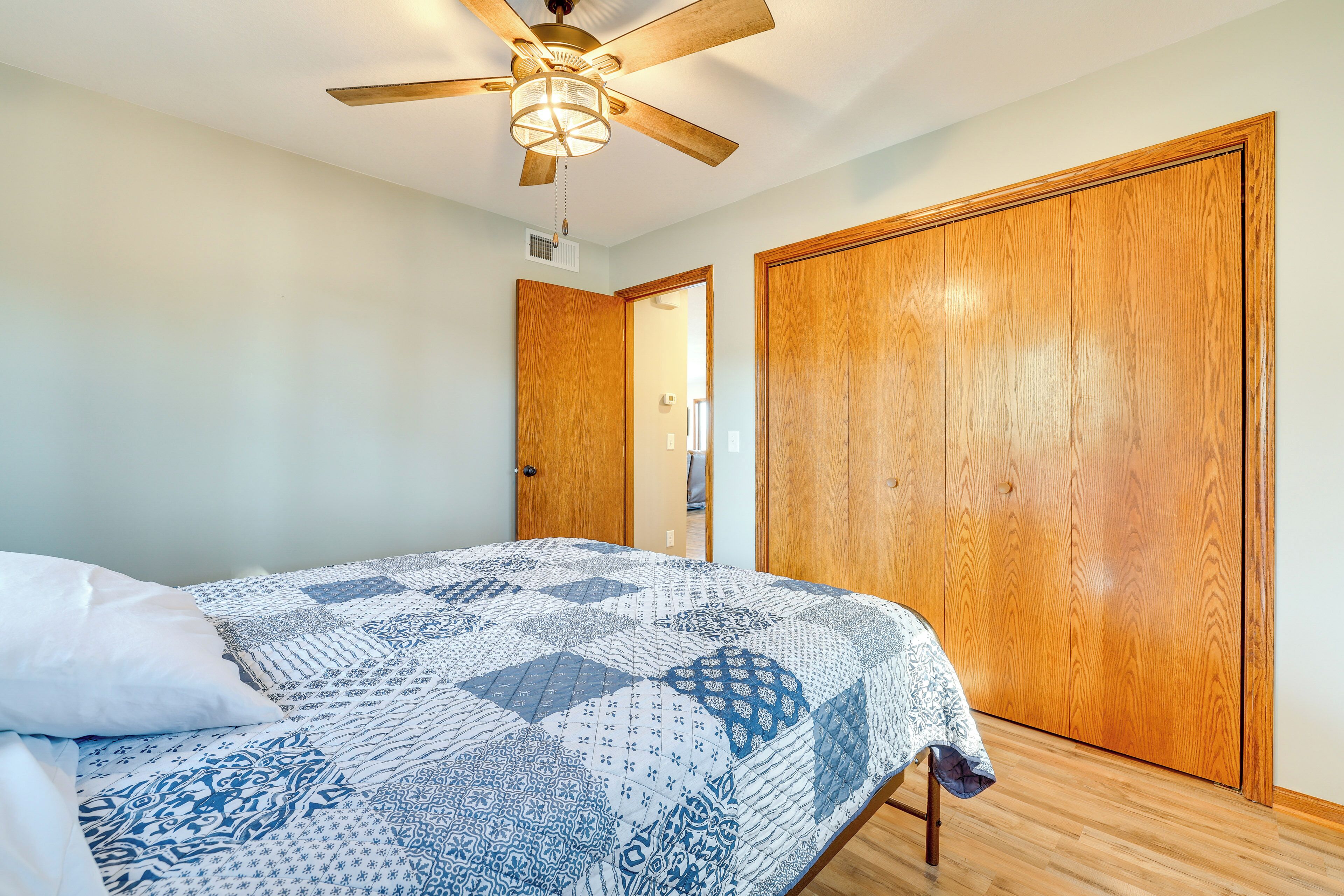 Ein Schlafzimmer mit Bett, Deckenventilator und Holzschränken.