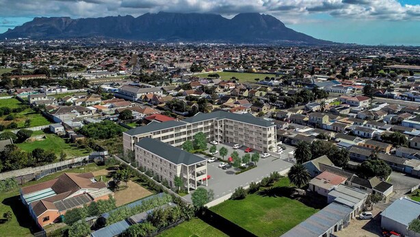 Vista aérea de una zona residencial con un edificio destacado en el centro, rodeado de casas y vegetación.
