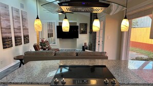 Une cuisine moderne dotée d’un plan de travail en granit, d’une cuisinière noire et d’un coin repas avec un canapé et une table.