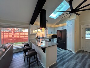 A modern kitchen with a central island, dark wood flooring, and a ceiling fan. - A&C WINDWARD COTTAGE # 1 (Victoria)