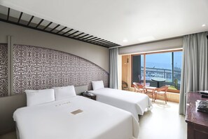 A hotel room with two beds, a balcony with a view of the sea, and a dining area with chairs and a table. - Bon Gaya Hotel (Boryeong)